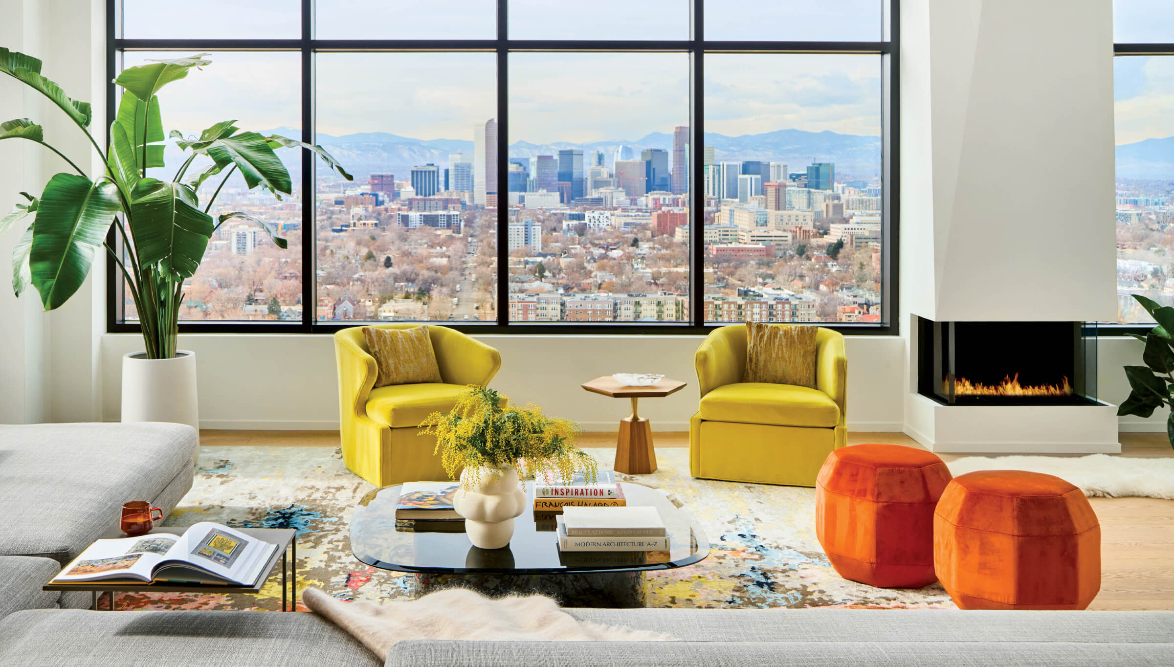 living room with bright yellow armchairs, orange ottomans and views of downtown Denver