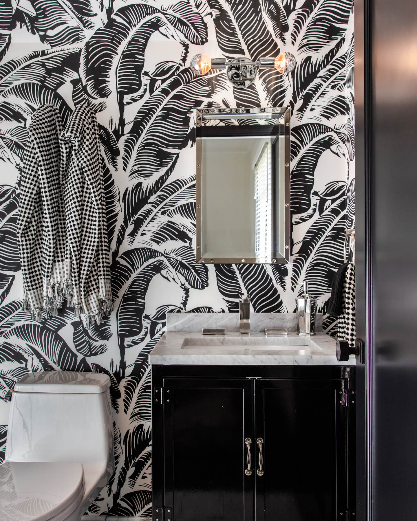 black and white botanical wallpaper in a half bathroom
