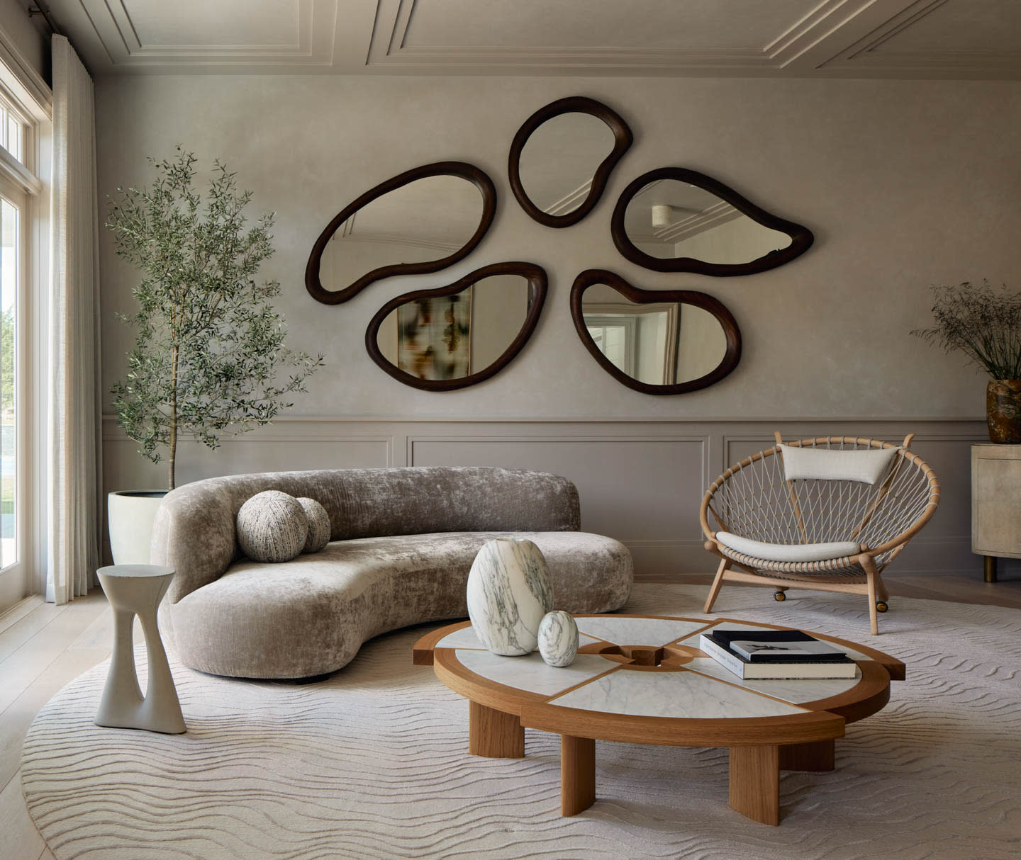 limewash walled living room with an abstract collection of mirrors above a sofa and coffee table