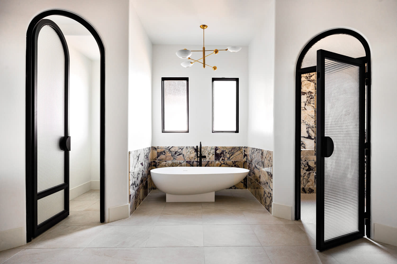 Bathroom with large freestanding tub in the center surrounded by purple-and-white marble by Kaitlyn Wolfe