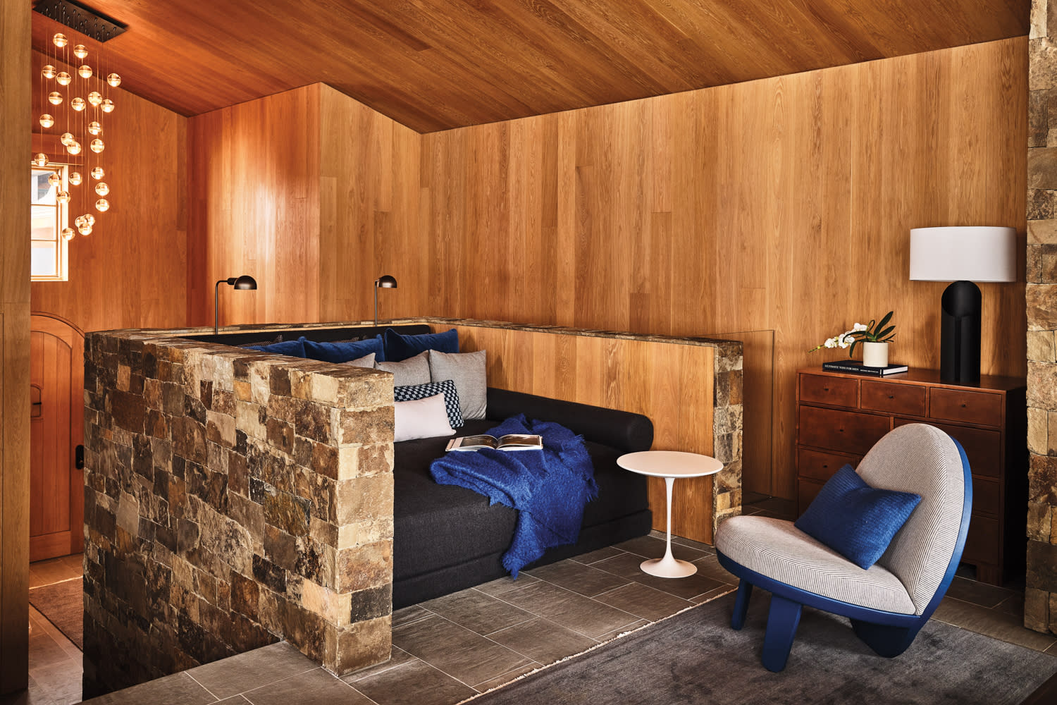 nook in wooden paneled room with stone surround and blue couch-like cushion