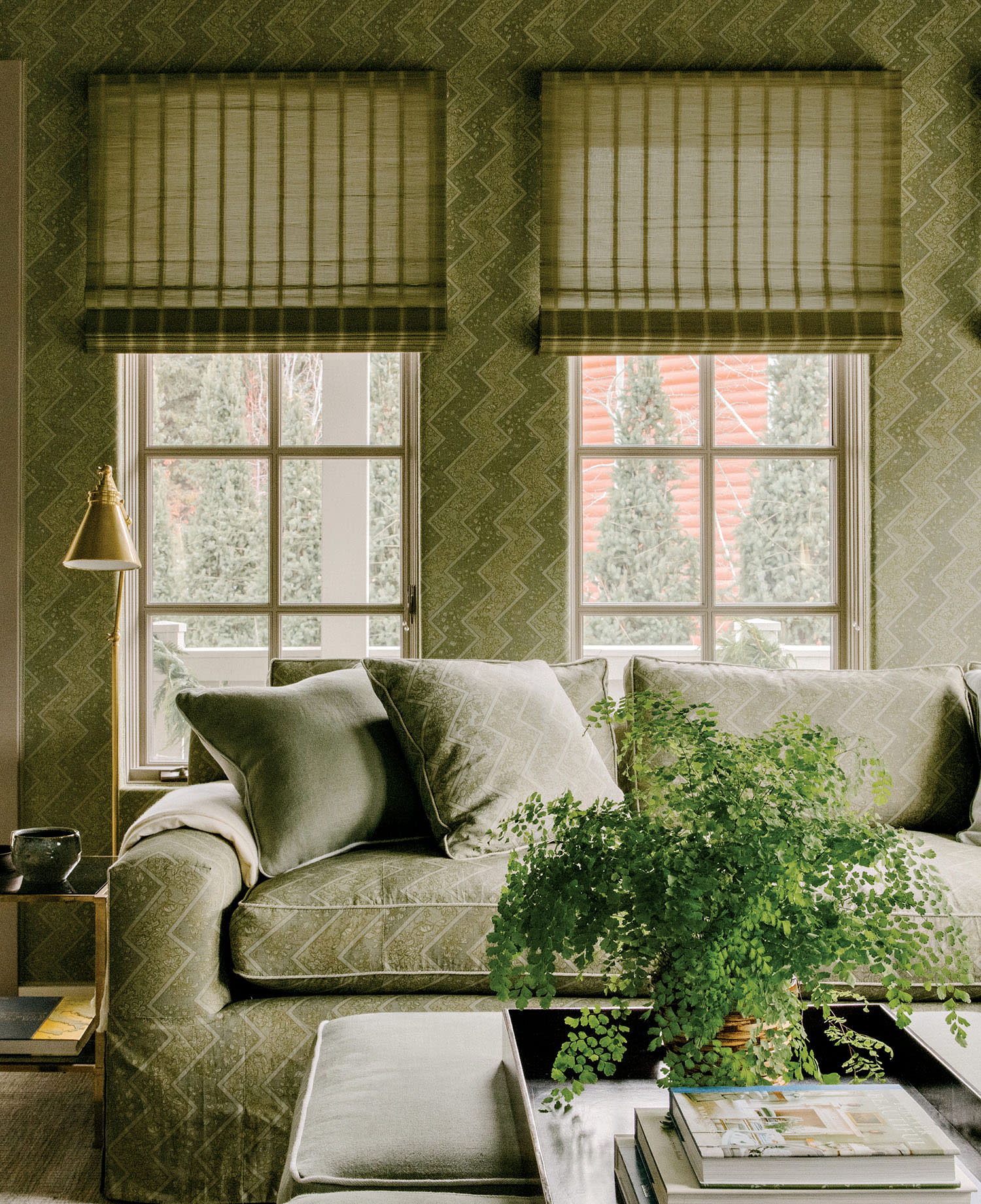 A neutral couch with matching throw pillows sits in front of a table with a plant on a wood tray.