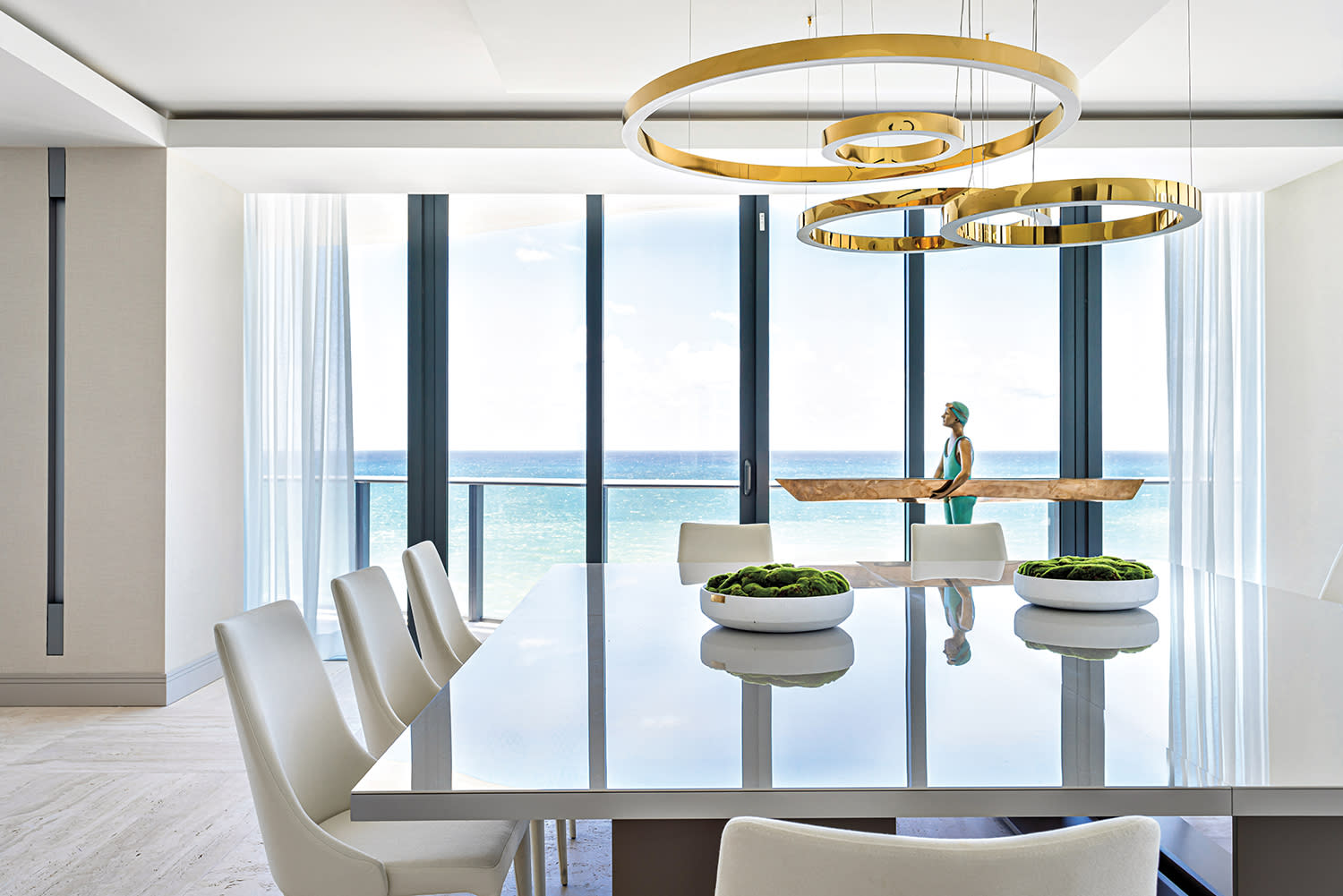 modern dining room with circular chandeliers above a rectangular table with white chairs