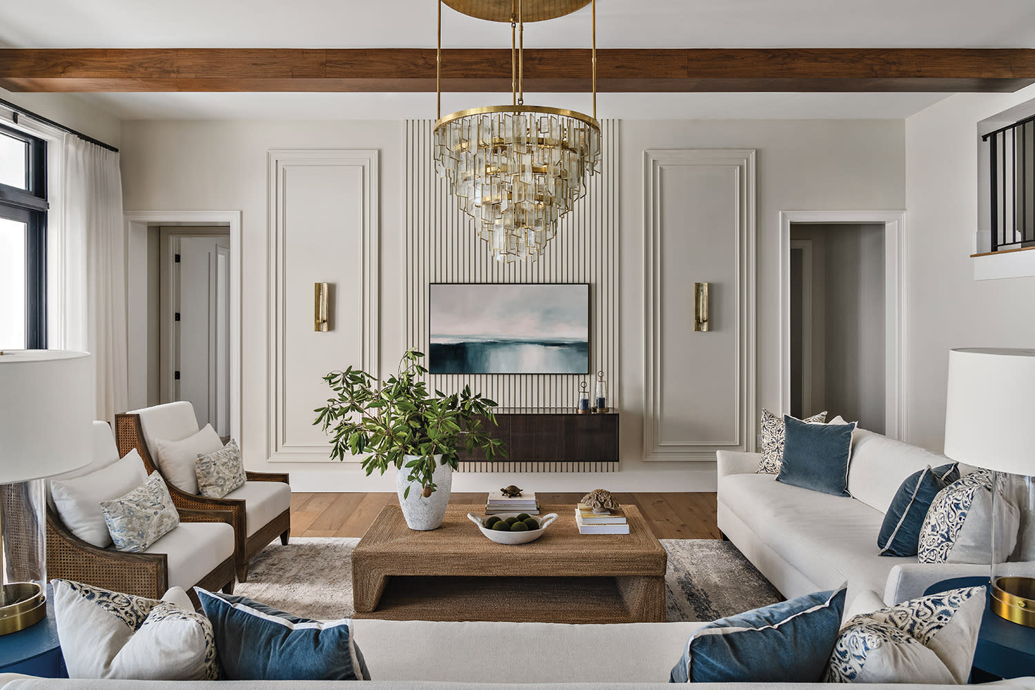 Elegant living room with white sofas, blue cushions, and wicker armchairs