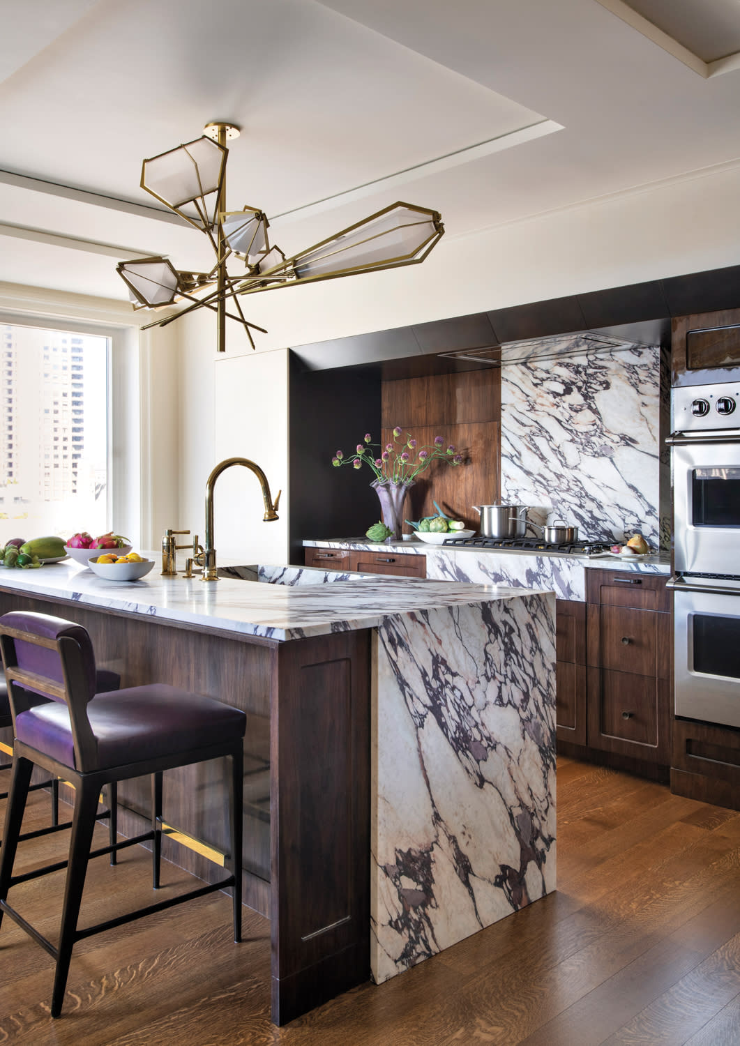 Kitchen designed by Sam Mitchell with marble cabinetry, gunmetal details and asymmetrical chandelier