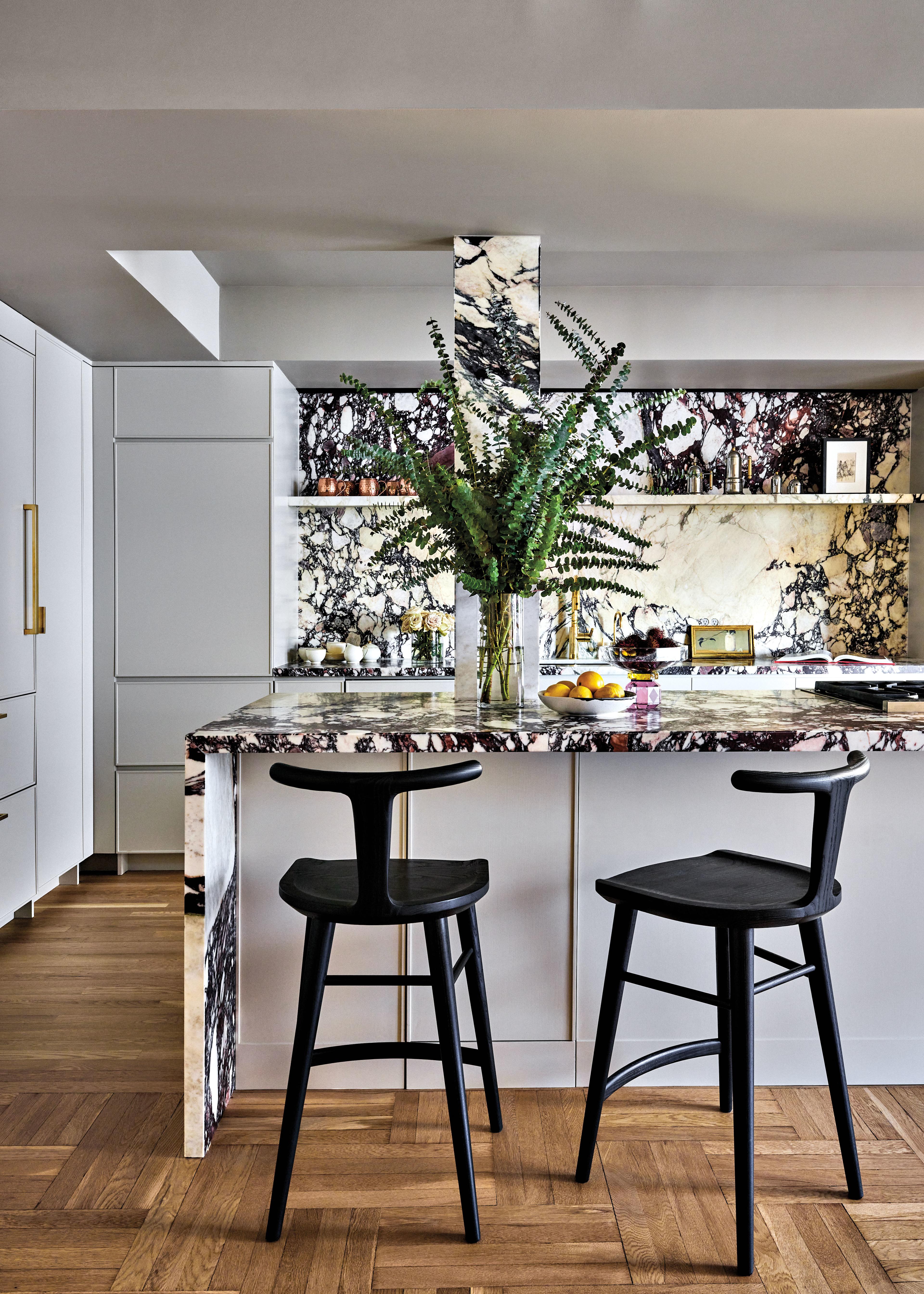 black stools in front of a black and white marble island in a kitchen